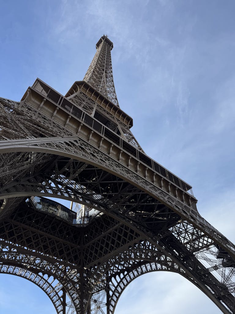 Capture of the iconic Eiffel Tower from below against a clear blue sky in Paris.